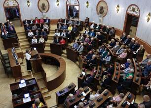 W Silesia Sejm Hall na Śląskim Konwencie Rad Seniorów siedzi uczestniczka, przygotowująca się do wystąpienia. (wygenerowano przez AI)