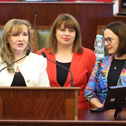 Trzy kobiety w strojach formalnych siedzą na podium, prowadzą dyskusję na Śląskim Konwencie Rad Seniorów. (wygenerowano przez AI)