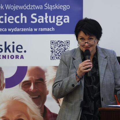 Podczas pierwszej edycji Śląskiego Konwentu Rad Seniorów w Sali Sejmu Śląskiego, kobieta przemawia na podium, podkreślając rolę seniorów w polityce regionu. (wygenerowano przez AI)