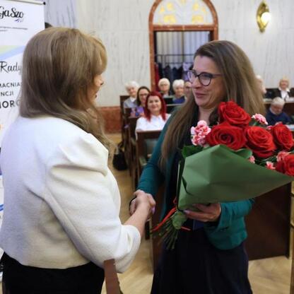 W Sali Sejmu Śląskiego podczas Śląskiego Konwentu Rad Seniorów dwie kobiety składają sobie ciepłe powitania, symbolizujące szacunek i celebrację. (wygenerowano przez AI)