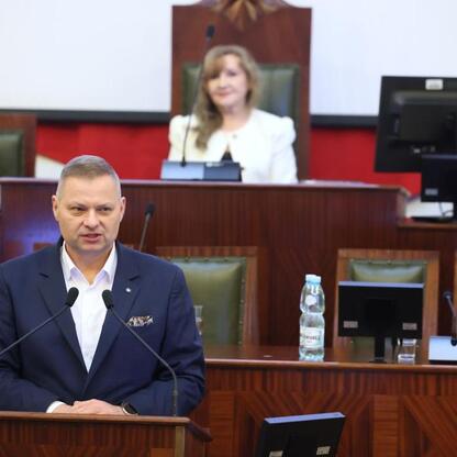 Członek Zarządu Województwa Śląskiego Rafał Adamczyk przemawia na podium podczas pierwszej edycji Śląskiego Konwentu Rad Seniorów. (wygenerowano przez AI)