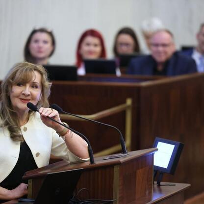 W Silesian Sejm Hall, na Śląskim Konwencie Rad Seniorów, kobieta gestykuluje podczas wystąpienia. (wygenerowano przez AI)
