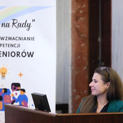 W Silesia Sejm Hall na Śląskim Konwencie Rad Seniorów siedzi uczestniczka, przygotowująca się do wystąpienia. (wygenerowano przez AI)