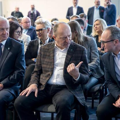 Grzegorz Boski, wicemarszałek województwa śląskiego, prowadzi spotkanie w konferencyjnym pomieszczeniu, omawiając postępy w inwestycjach drogowych i kolejowych w północnym Śląsku. (wygenerowano przez AI)