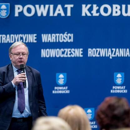 Wicemarszałek Grzegorz Boski przemawia na spotkaniu w Kłobucku, omawiając postępy w modernizacji dróg i reaktywacji kolejowego połączenia. (wygenerowano przez AI)