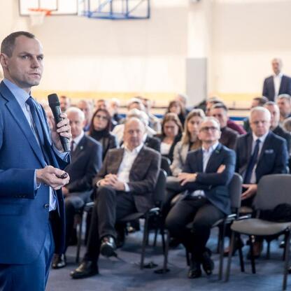 Grzegorz Boski, wicemarszałek województwa śląskiego, przemawia na spotkaniu w Kłobucku, omawiając postępy w przebudowie dróg i reaktywacji kolejowego połączenia. (wygenerowano przez AI)