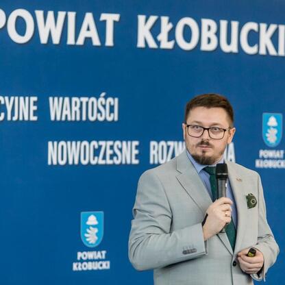 Wicemarszałek Grzegorz Boski przemawia na konferencji prasowej o przebudowanych drogach i reaktywowanym połączeniu kolejowym w Kłobucku. (wygenerowano przez AI)
