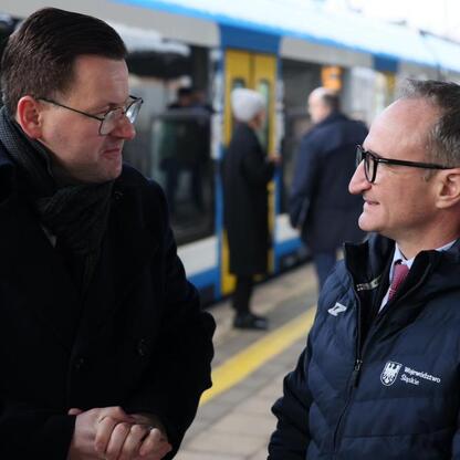 Grzegorz Boski, wicemarszałek Województwa Śląskiego, rozmawia z kolegą na stacji kolejowej. (wygenerowano przez AI)