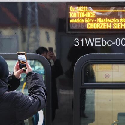 Nowy pociąg Kolei Śląskich na trasie Chorzowa Batorego - Chorzew Siemkowice. Pasażerowie fotografują tablicę z informacjami o trasie. (wygenerowano przez AI)