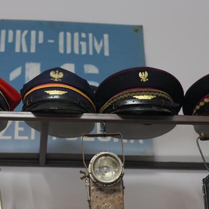 Display of uniform hats and headlamps, likely from a railway context, with a sign reading 