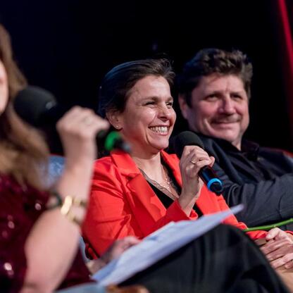 Zdjęcie przedstawia moment z ceremonii wręczenia nagród Marszałka Województwa Śląskiego Culture Awards, która odbyła się w Kinoteatrze Rialto w Katowicach. Trzech osób, prawdopodobnie sędziów lub prez (wygenerowano przez AI)