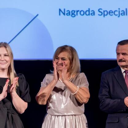 Trzech uczestników nagrody specjalnej Marszałka Województwa Śląskiego klaskają podczas uroczystości w Kinoteatrze Rialto w Katowicach. (wygenerowano przez AI)