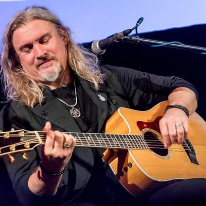 Muzyk gra na gitarze akustycznej podczas ceremonii wręczenia nagród Marszałka Województwa Śląskiego Culture Awards. (wygenerowano przez AI)