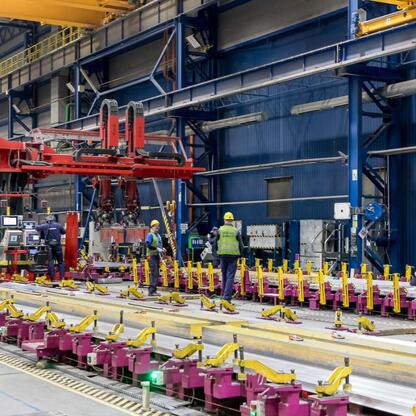 Wnętrze fabryki Alstom w Chorzowie, gdzie produkuje się szybkie dwupiętrowe pociągi dla PKP Intercity. Pracownicy w ochronie wykonują montaż. (wygenerowano przez AI)