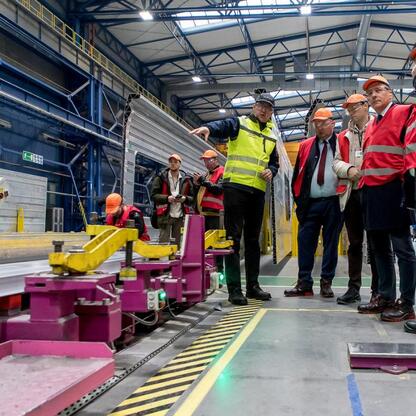 Zdjęcie przedstawia pracowników i urzędników w fabryce Alstom w Chorzowie, gdzie produkowane są pociągi ekspresowe dla PKP Intercity. (wygenerowano przez AI)