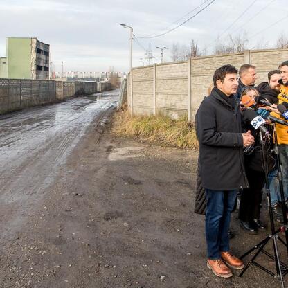 W czasie briefingu prasowego w Katowicach-Szopienicach, przedstawiciele lokalnych władz opowiadają o usuwaniu niebezpiecznych odpadów z terenu dawnego składowiska. (wygenerowano przez AI)