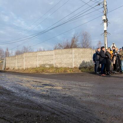 Zdjęcie przedstawia grupę ludzi pracujących na miejscu zlikwidowanego składowiska niebezpiecznych odpadów w Katowicach-Szopienicach. (wygenerowano przez AI)
