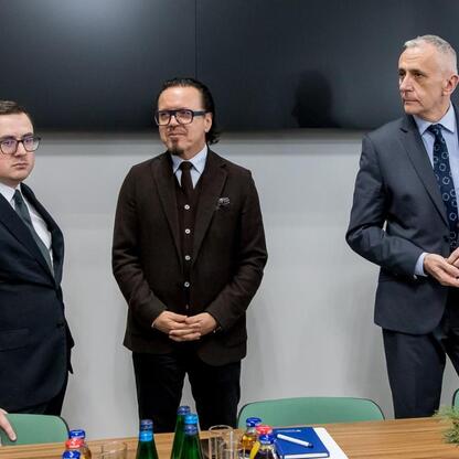 Trzech mężczyzn w garniturach w konferencyjnym pomieszczeniu, omawiających przyszłość górnictwa. (wygenerowano przez AI)