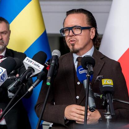 Na zdjęciu przedstawiono formalną konferencję prasową, gdzie przedstawiciel rządu i przedstawiciel przemysłu energetycznego omawiają przyszłość górnictwa, z uwzględnieniem flag Polski i Ukrainy. (wygenerowano przez AI)