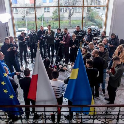 Wśród dziennikarzy i oficjalnych zebrał się w nowoczesnym pomieszczeniu z oknami, omawiając przyszłość górnictwa. (wygenerowano przez AI)