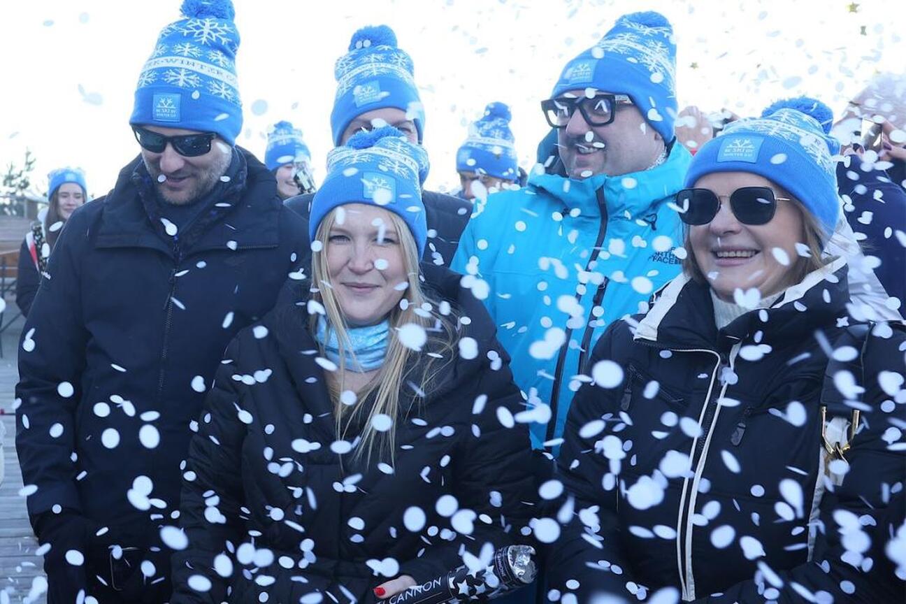 Mężczyzna w czarnym garniturze i okularach przemawia do mikrofonu na inauguracji sezonu zimowego w Beskidach. (wygenerowano przez AI)