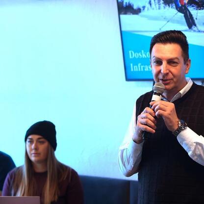 Mężczyzna przemawia na konferencji o zimowych atrakcjach w Beskidach, podkreślając rozwój turystyki w regionie. (wygenerowano przez AI)