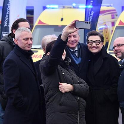 Ambulanse z logo Wojewódzkiego Pogotowia Ratunkowego, zimowe ubrania, selfie przed nowoczesnymi karetkami. (wygenerowano przez AI)