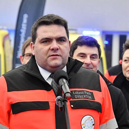 Łukasz Pach, dyrektor WPR w Katowicach, przemawia na briefingu prasowym o nowych ambulansach. (wygenerowano przez AI)