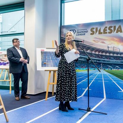 Joanna Bojczuk, Członkini Zarządu Województwa Śląskiego, przemawia na imprezie sportowej, wspierając wystawę fotografii i nowy eksponat w muzeum Superauto.pl Stadionu Śląskiego. (wygenerowano przez AI)