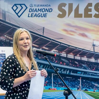 Joanna Bojczuk, członkini Zarządu Województwa Śląskiego, przemawia na mikrofonie podczas konferencji prasowej w ramach Wanda Diamond League. (wygenerowano przez AI)