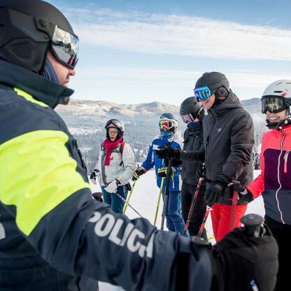 Grupa narciarzy i snowboardzistów z policjantem na pierwszym planie, promocja bezpieczeństwa w zimie. (wygenerowano przez AI)