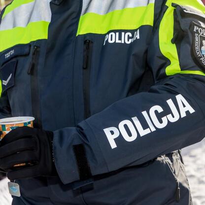 Policjant w kamizelce odblaskowej, trzymający kubek, promujący bezpieczeństwo w zimie. (wygenerowano przez AI)