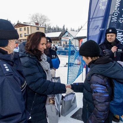 Grupa osób w zimowym stroju, promujące bezpieczeństwo w zimowych sportach na śniegu. (wygenerowano przez AI)