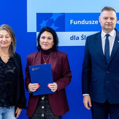 Trzech ludzi stoi przed niebieskim tłem z napisem 