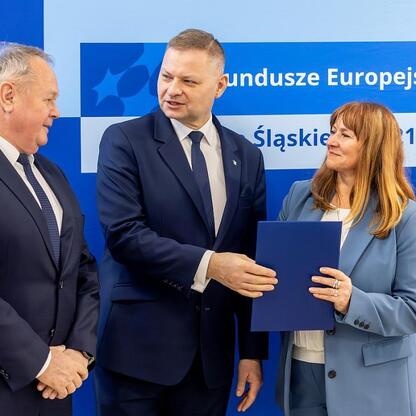 Członek Zarządu Województwa Rafał Adamczyk wraz z dwoma współpracownikami prezentuje program Funduszy Europejskich Śląskie 2021-2027. (wygenerowano przez AI)