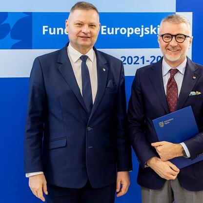 Dwóch mężczyzn w strojach formalnych przedstawiających logo i tekst 