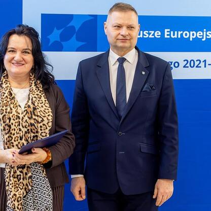 Członek Zarządu Województwa Rafał Adamczyk i nieznana osoba przedstawiają logo i informacje o funduszach dla przedszkoli w Śląsku. (wygenerowano przez AI)