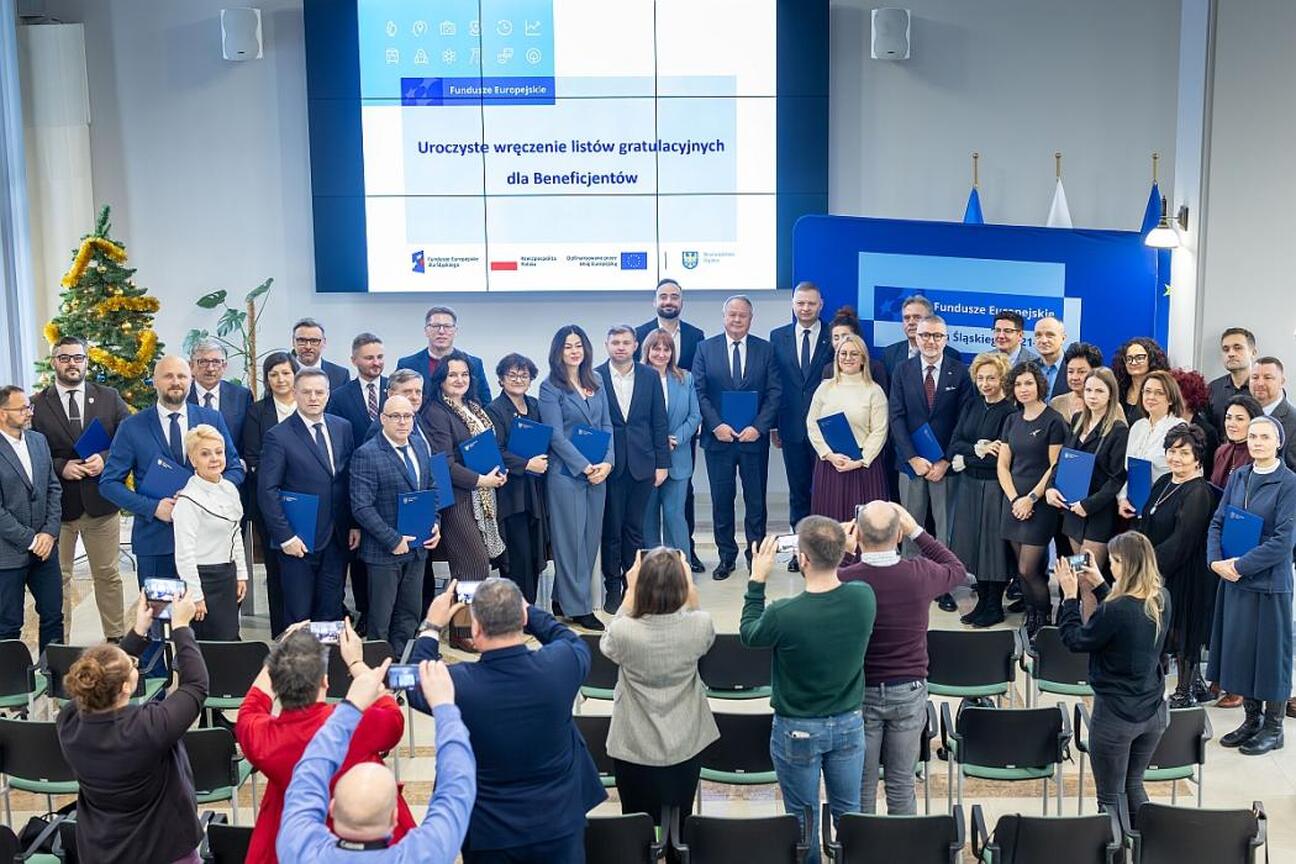Rafał Adamczyk, członek zarządu województwa śląskiego, prezentuje projekt na tle funduszy europejskich wspierających edukację przedszkolną. (wygenerowano przez AI)