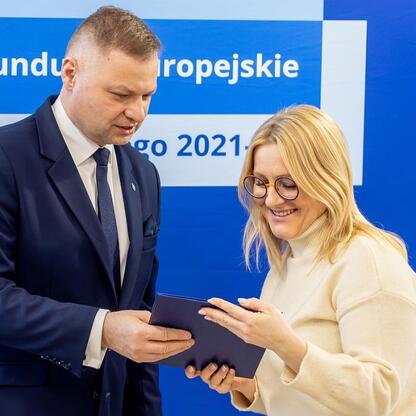 Rafał Adamczyk, członek zarządu województwa śląskiego, prezentuje projekt na tle funduszy europejskich wspierających edukację przedszkolną. (wygenerowano przez AI)