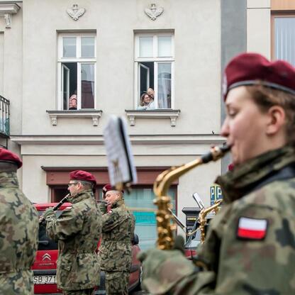 Inauguracja Bielska-Białej jako Polskiej Stolicy Kultury w 2026 roku. Militarna orkiestra gra na Placu Ratuszowym, publiczność z okien. (wygenerowano przez AI)