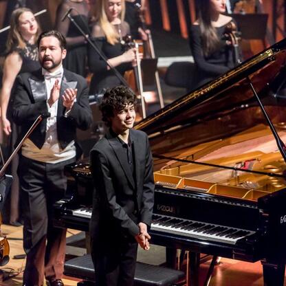 Moment inauguracji Bielska-Białej jako Polskiej Stolicy Kultury w 2026 roku. Pianista śmieje się i kłapie, tło: orkiestra. (wygenerowano przez AI)