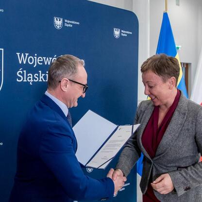 Grzegorz Boski, wicemarszałek Śląskiego, wręcza beneficjentom symboliczne listy gratulacyjne. (wygenerowano przez AI)