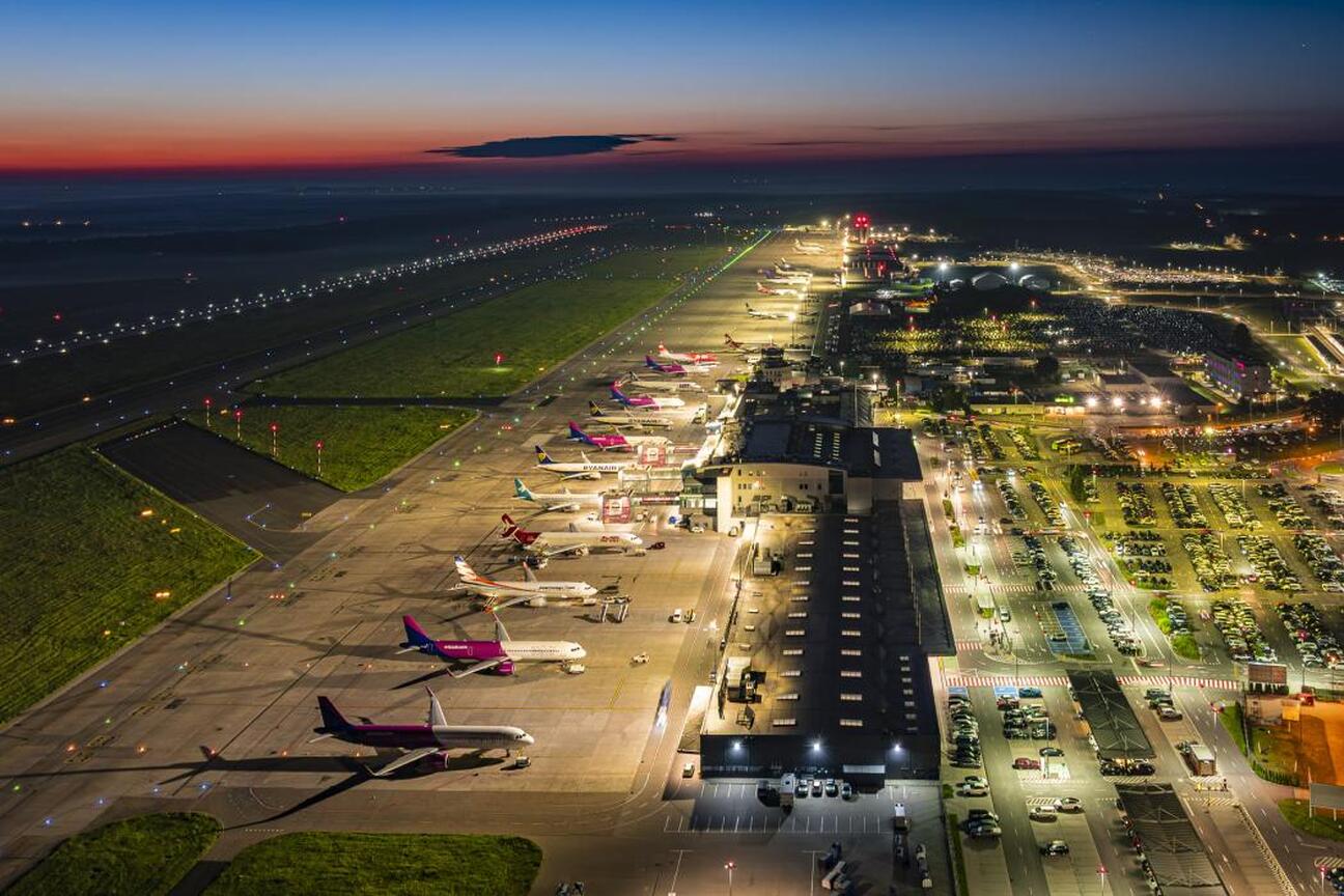 Katowice Airport, oświetlone terminaly i lotniskowe drogi, widoczne wczesnym wieczorem. (wygenerowano przez AI)