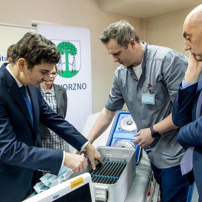 Zdjęcie przedstawia grupę pracowników w szpitalu, którzy inspektują medyczną technikę, wskazując na inwestycje w bezpieczeństwo publiczne. (wygenerowano przez AI)