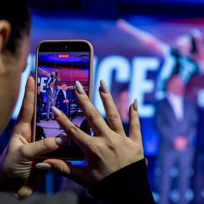 Moment z PreZero Arena w Gliwicach, gdzie kobieta rejestruje wydarzenie na ekranie smartfona, z widocznym na tle dużym ekranem z napisem 