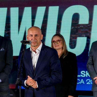 Wicemarszałek Leszek Pietraszek przemawia na scenie podczas powitalnego wydarzenia w Gliwicach, związanych z powrotem prestiżowych turniejów siatkarskich. (wygenerowano przez AI)