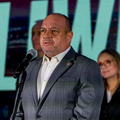Mężczyzna w garniturze przemawia do mikrofonu na konferencji prasowej w Gliwicach. (wygenerowano przez AI)