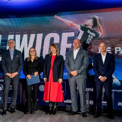 Grupa osób w strojach formalnych na scenie podczas Volleyball Nations League w Gliwicach. (wygenerowano przez AI)