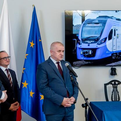 Podpis pod zdjęciem: Grzegorz Boski, wicemarszałek Województwa Śląskiego, podpisuje dokument na kontrakt dotyczący zakupu nowoczesnych pociągów dla Kolei Śląskich. (wygenerowano przez AI)