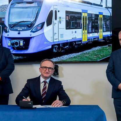 Wicemarszałek Województwa Śląskiego Grzegorz Boski podpisuje dokument na ceremonii zakupu nowych elektrycznych zespołów trakcyjnych dla Kolei Śląskich. (wygenerowano przez AI)
